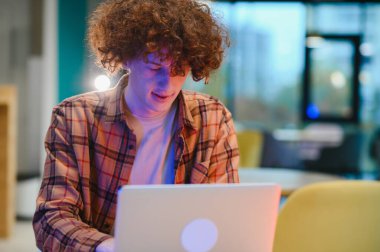 Modern cep telefonu ve dizüstü bilgisayar teknolojisi olan neşeli bin yıllık blog yazarının portresi serbest yaşam tarzının tadını çıkaran, optik gözlüklü mutlu hippi adam sokak kafesinde cep telefonu ve netbook kullanıyor.