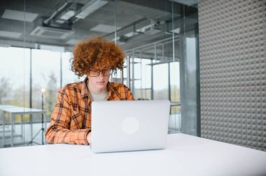 Yetenekli erkek programcı aşınma gözlükler gözleri koruma serbest dizüstü bilgisayar üzerinden üzerinde çalışırken, akıllı öğrenci netbook eğitsel izlerken kafeterya derslerde öğrenme e memnun..