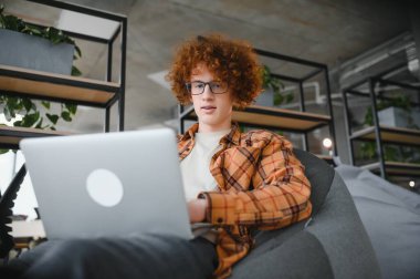 Kafkasyalı hippi, kahve dükkanında mesai yapıyor. Moda gözlüklü erkek, kafeteryada modern laptop cihazıyla oturuyor..