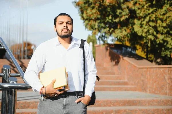 本を持って大学に立つ男性インド人学生 — ストック写真