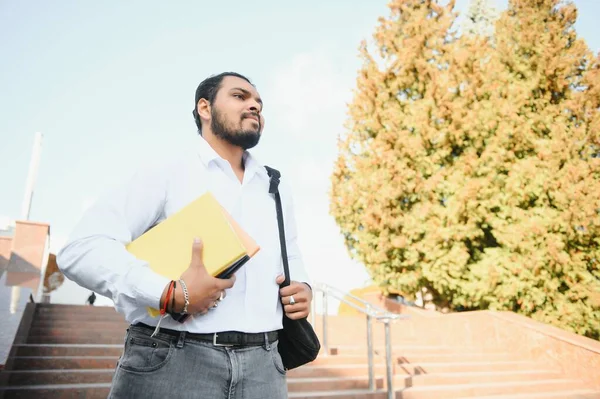 本を持って大学に立つ男性インド人学生 — ストック写真