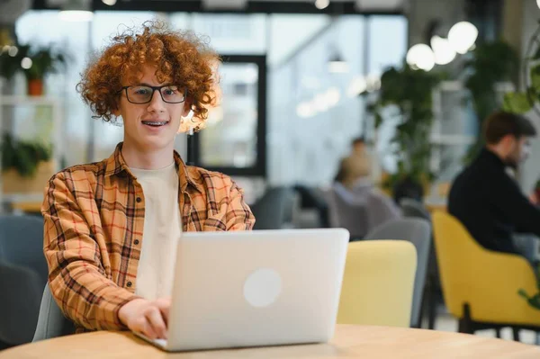 stock image Skilled male programmer wear spectacles for eyes protection while working on freelance via laptop computer,clever student watching tutorial on netbook satisfied e learning courses in cafeteria.