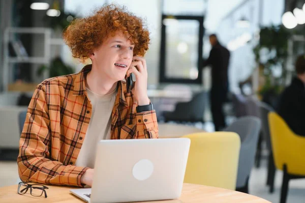 stock image Thoughtful guy freelancer in casual clothes browsing laptop while working on project on terrace of cafe in daytime