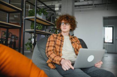 Gündüz vakti kafenin terasında proje üzerinde çalışırken gündelik kıyafetlerle bilgisayara göz atan düşünceli bir adam.