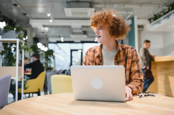 stock image Thoughtful guy freelancer in casual clothes browsing laptop while working on project on terrace of cafe in daytime