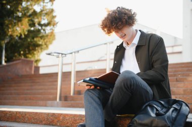 Üniversite nin yakınındaki sınıflar arasında mola alan heyecanlı öğrenci, açık havada kameraya gülümsüyor.