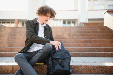 Üniversite nin yakınındaki sınıflar arasında mola alan heyecanlı öğrenci, açık havada kameraya gülümsüyor.