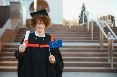 Mezuniyet diplomasıyla ışıldayan yakışıklı bir mezun.