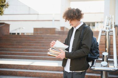 Üniversite nin yakınındaki sınıflar arasında mola alan heyecanlı öğrenci, açık havada kameraya gülümsüyor.