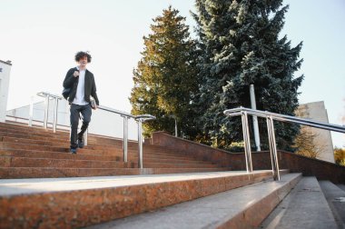 Çanta ile kampüste duran bir mutlu erkek öğrenci portresi.