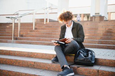 Üniversite nin yakınındaki sınıflar arasında mola alan heyecanlı öğrenci, açık havada kameraya gülümsüyor.