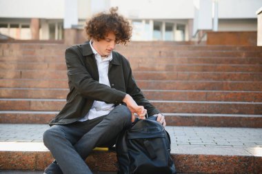 Üniversite nin yakınındaki sınıflar arasında mola alan heyecanlı öğrenci, açık havada kameraya gülümsüyor.