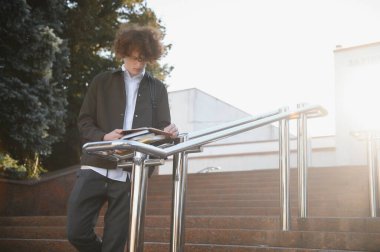 Üniversite nin yakınındaki sınıflar arasında mola alan heyecanlı öğrenci, açık havada kameraya gülümsüyor.