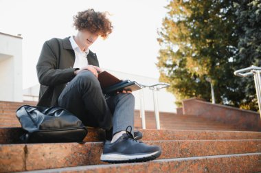 Üniversite nin yakınındaki sınıflar arasında mola alan heyecanlı öğrenci, açık havada kameraya gülümsüyor.