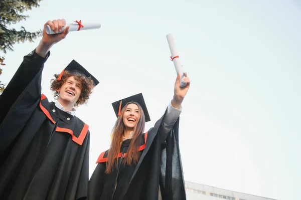 졸업생들의 모자와 가운을 밖에서 배경으로 학생들 졸업장 두루마리를 — 스톡 사진
