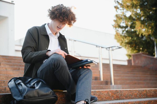 Portrait of a happy male student standing on campus with bag.