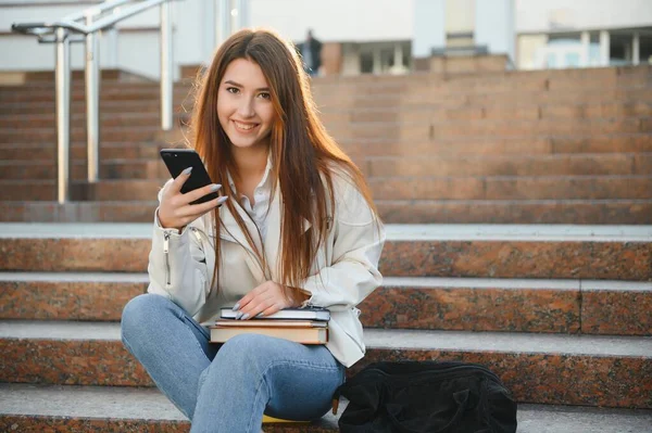 stock image Young girl student smiling against university. Cute girl student holds folders and notebooks in hands. Learning, education concept.