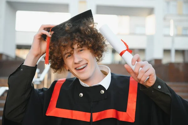 Szczęśliwy Uśmiechnięty Absolwent Uniwersytetu Płaszczu Trzymając Dyplom Ręce Wyrażając Szczęście — Zdjęcie stockowe