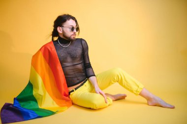 Eşcinsel adam renkli arka plan stüdyo resminde izole edilmiş gökkuşağı çizgili bayrak tutuyor. Insanlar yaşam tarzı lgbtq konsepti.
