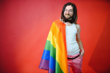 Beyaz arka planda LGBT Rainbow bayrağı taşıyan gururlu, yakışıklı genç bir adam. Eşcinsel gurur bayrağı taşıyan adam