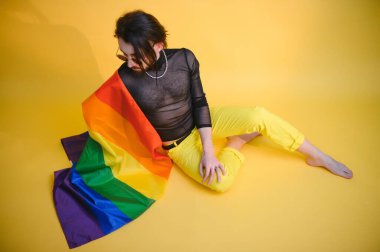 Eşcinsel adam renkli arka plan stüdyo resminde izole edilmiş gökkuşağı çizgili bayrak tutuyor. Insanlar yaşam tarzı lgbtq konsepti.