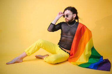 Eşcinsel adam renkli arka plan stüdyo resminde izole edilmiş gökkuşağı çizgili bayrak tutuyor. Insanlar yaşam tarzı lgbtq konsepti.