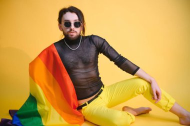 Beyaz arka planda LGBT Rainbow bayrağı taşıyan gururlu, yakışıklı genç bir adam. Eşcinsel gurur bayrağı taşıyan adam