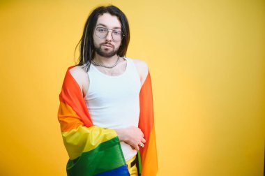 Beyaz arka planda LGBT Rainbow bayrağı taşıyan gururlu, yakışıklı genç bir adam. Eşcinsel gurur bayrağı taşıyan adam