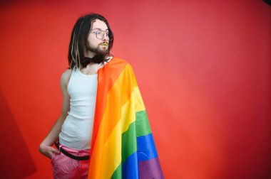 Eşcinsel adam renkli arka plan stüdyo resminde izole edilmiş gökkuşağı çizgili bayrak tutuyor. Insanlar yaşam tarzı lgbtq konsepti.
