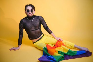 Eşcinsel adam renkli arka plan stüdyo resminde izole edilmiş gökkuşağı çizgili bayrak tutuyor. Insanlar yaşam tarzı lgbtq konsepti.