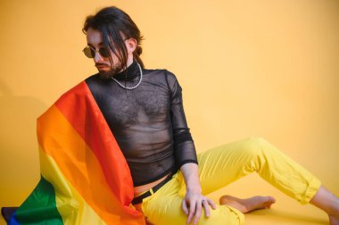 Beyaz arka planda LGBT Rainbow bayrağı taşıyan gururlu, yakışıklı genç bir adam. Eşcinsel gurur bayrağı taşıyan adam