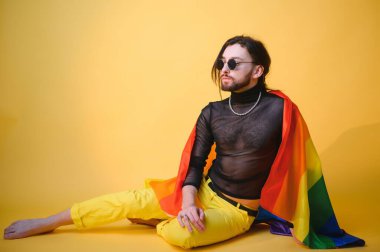 Eşcinsel adam renkli arka plan stüdyo resminde izole edilmiş gökkuşağı çizgili bayrak tutuyor. Insanlar yaşam tarzı lgbtq konsepti.
