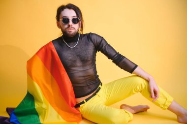 Eşcinsel adam renkli arka plan stüdyo resminde izole edilmiş gökkuşağı çizgili bayrak tutuyor. Insanlar yaşam tarzı lgbtq konsepti.