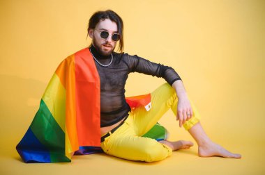 Eşcinsel adam renkli arka plan stüdyo resminde izole edilmiş gökkuşağı çizgili bayrak tutuyor. Insanlar yaşam tarzı lgbtq konsepti.