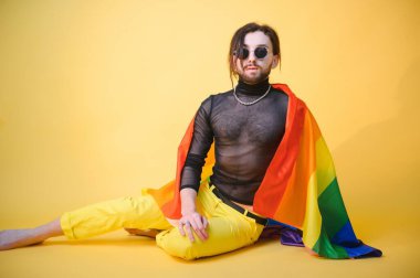 Eşcinsel adam renkli arka plan stüdyo resminde izole edilmiş gökkuşağı çizgili bayrak tutuyor. Insanlar yaşam tarzı lgbtq konsepti.