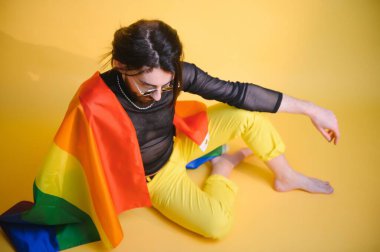 Eşcinsel adam renkli arka plan stüdyo resminde izole edilmiş gökkuşağı çizgili bayrak tutuyor. Insanlar yaşam tarzı lgbtq konsepti.