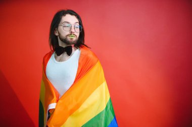 Eşcinsel adam renkli arka plan stüdyo resminde izole edilmiş gökkuşağı çizgili bayrak tutuyor. Insanlar yaşam tarzı lgbtq konsepti.