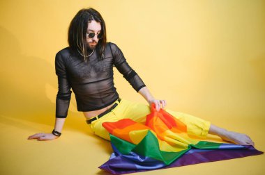 Renkli arka plan stüdyo resmine izole edilmiş parlak pembe çizgili gökkuşağı çizgili bayraklı eşcinsel adam. Insanlar yaşam tarzı lgbtq konsepti.