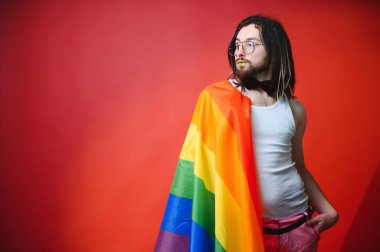 Beyaz arka planda LGBT Rainbow bayrağı taşıyan gururlu, yakışıklı genç bir adam. Eşcinsel gurur bayrağı taşıyan adam