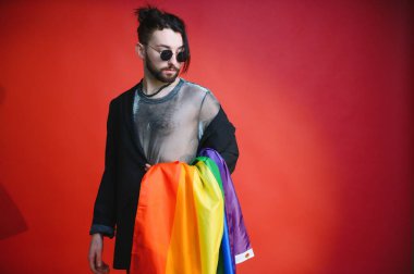 Beyaz arka planda LGBT Rainbow bayrağı taşıyan gururlu, yakışıklı genç bir adam. Eşcinsel gurur bayrağı taşıyan adam