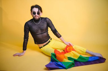 Eşcinsel adam renkli arka plan stüdyo resminde izole edilmiş gökkuşağı çizgili bayrak tutuyor. Insanlar yaşam tarzı lgbtq konsepti.
