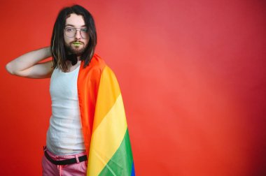Eşcinsel adam renkli arka plan stüdyo resminde izole edilmiş gökkuşağı çizgili bayrak tutuyor. Insanlar yaşam tarzı lgbtq konsepti.
