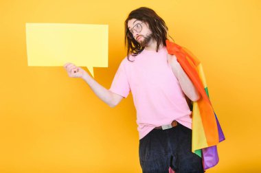 Beyaz arka planda LGBT Rainbow bayrağı taşıyan gururlu, yakışıklı genç bir adam. Eşcinsel gurur bayrağı taşıyan adam