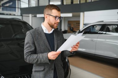 Adam akıllı müşteri, takım elbiseli müşteri, otomobili seçer, kenara bakar, galeride yeni otomobil almak ister.