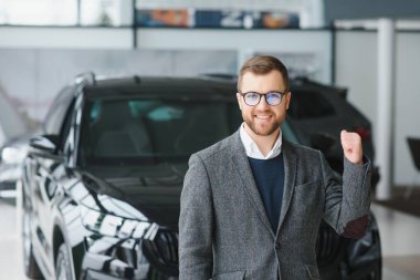 Galeride arabanın yanında duran takım elbiseli yakışıklı bir satıcının portresi..