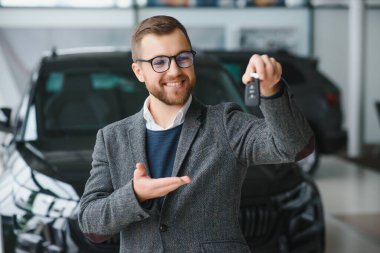 Yeni bir arabanın mutlu sahibi. Günlük giysiler içinde duygusal açıdan yakışıklı bir adam, galeriden bir araba almaktan mutlu.