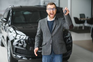 Yeni bir arabanın mutlu sahibi. Günlük giysiler içinde duygusal açıdan yakışıklı bir adam, galeriden bir araba almaktan mutlu.