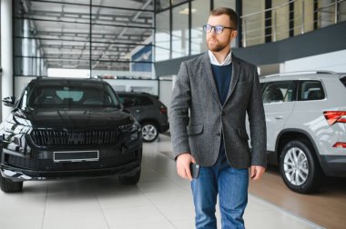 İyi görünümlü, neşeli ve samimi satıcı bir araba salonu veya showroom pozlar