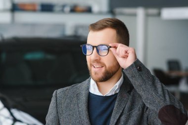 İyi görünümlü, neşeli ve samimi satıcı bir araba salonu veya showroom pozlar