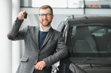 Galeride arabanın yanında duran takım elbiseli yakışıklı bir satıcının portresi..